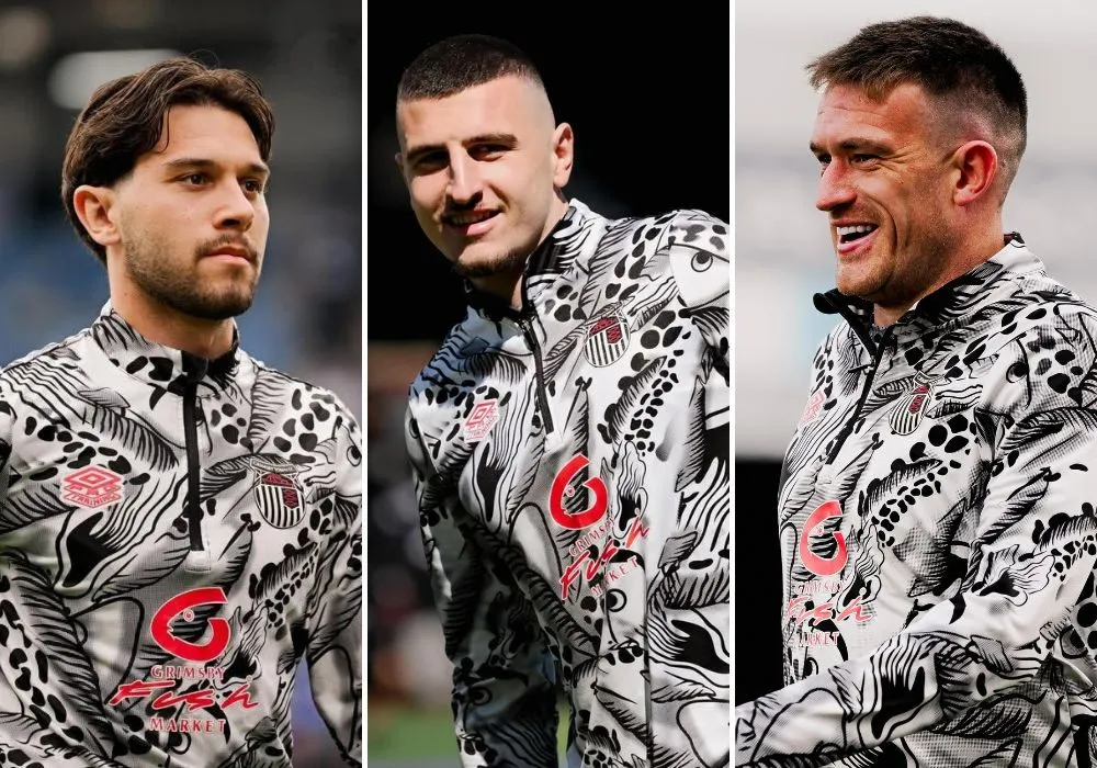 Grimsby Town players wearing the Grimsby Fish Market sponsored warm-up tops pre-game. They have a haddock design with the market logo on the front.