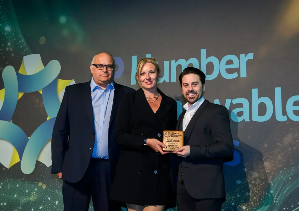 Vicky Powell, director of UK offshore operations at RWE, presents the Ports and Logistics Company of the Year Award to Andrew Oliver, left, and Ben Walker, of Grimsby Fish Dock Enterprises, the group company behind Port of Grimsby East. They are all dressed smartly for the formal dinner and on stage at the venue.