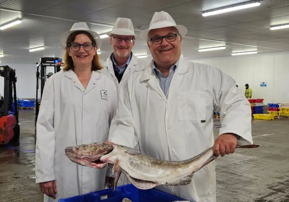 Three people and a cod on Grimsby Fish Market.