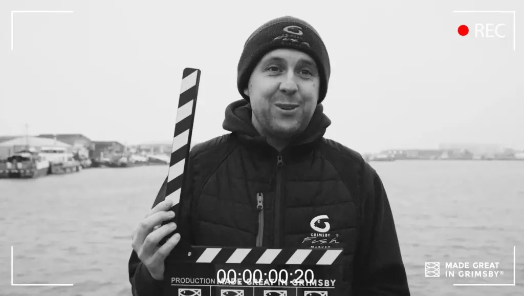 Danny Payne stood on Port of Grimsby East with a clapperboard or production slate, as they are widely known.