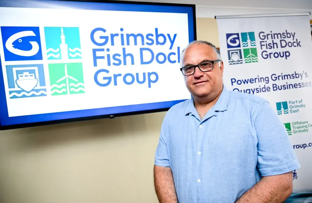 A man stood in front of a monitor and banner displaying the new brand identity.